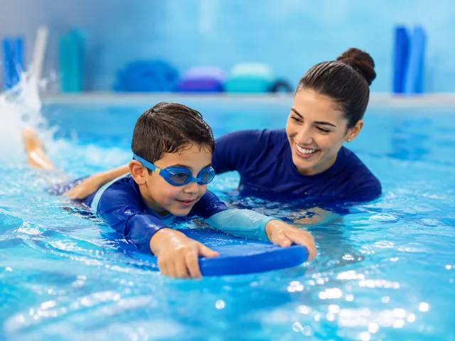 Niño aprendiendo a nadar con la guía de una instructora